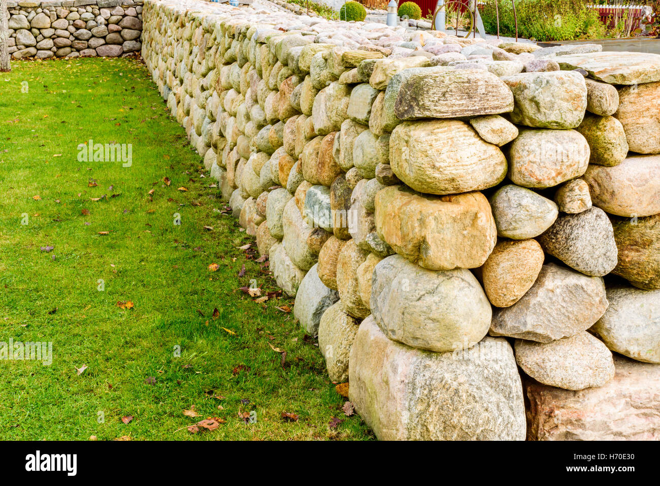 Glatt und gut gebaute Steinmauer mit grünen Rasen auf der einen Seite. Stockfoto
