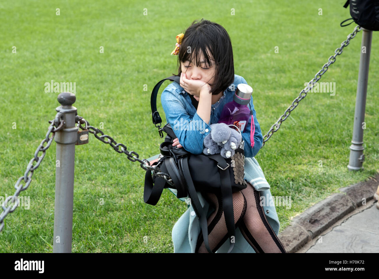Müde junge asiatische Touristen sitzen auf Zaun, Stockfoto