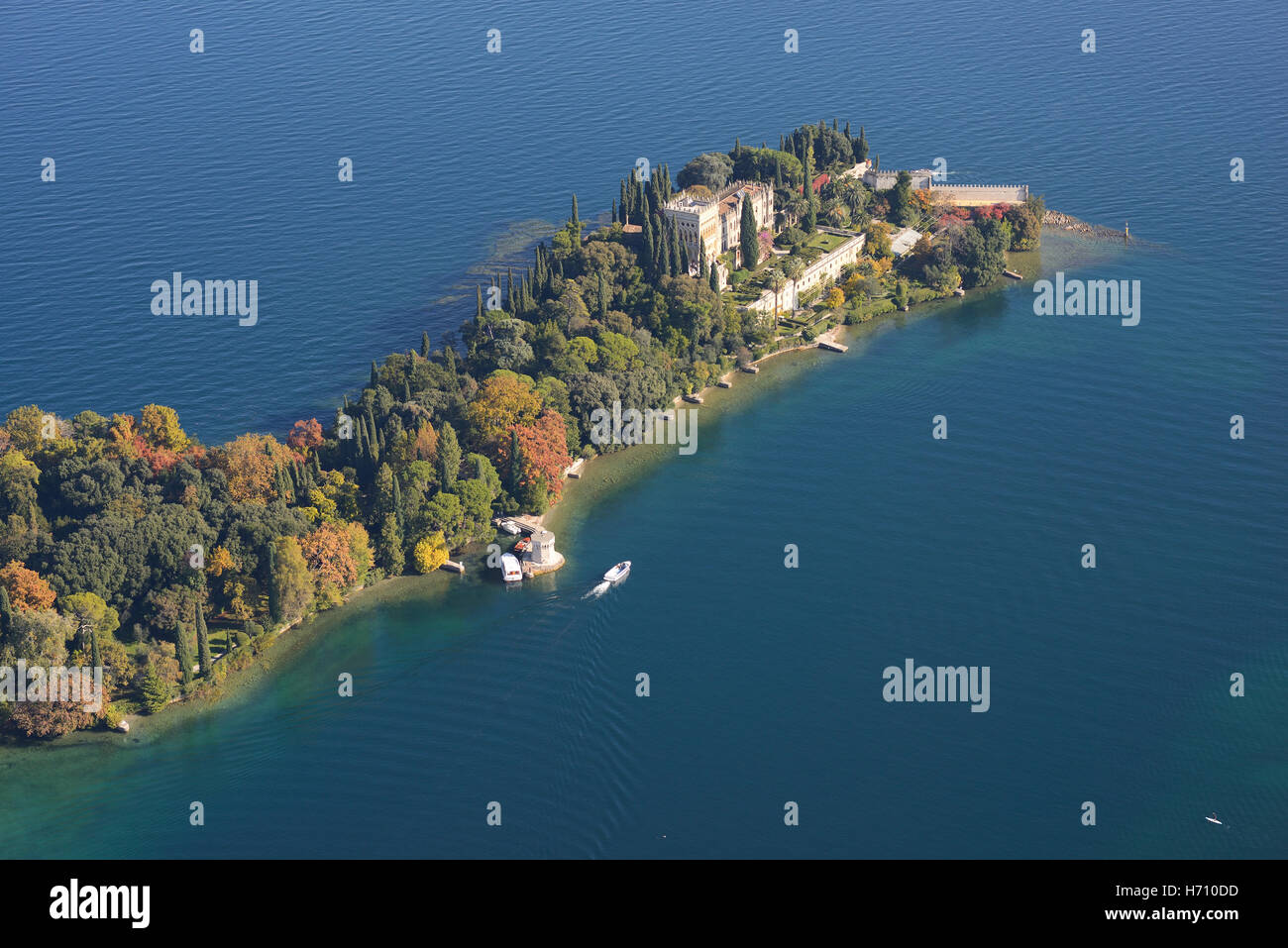 LUFTAUFNAHME. Bewaldete Insel im Herbst und eine venezianische neugotische Villa. Isola del Garda, Gardasee, Provinz Brescia, Lombardei, Italien. Stockfoto