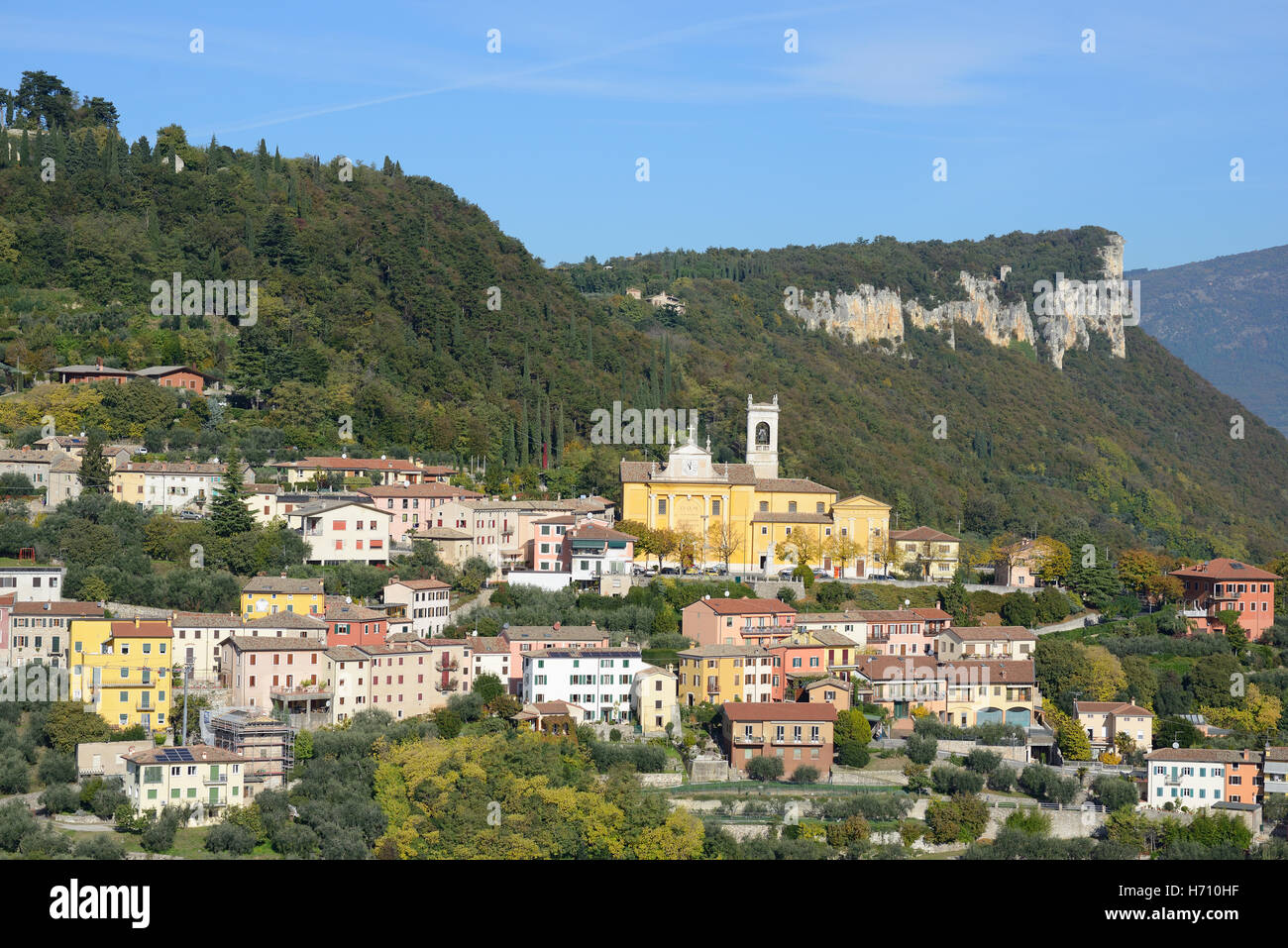 LUFTAUFNAHME. Stadt auf einem Hügel mit einem Hintergrund aus Wald und Klippen. Cavaion Veronese, Provinz Verona, Venetien, Italien. Stockfoto