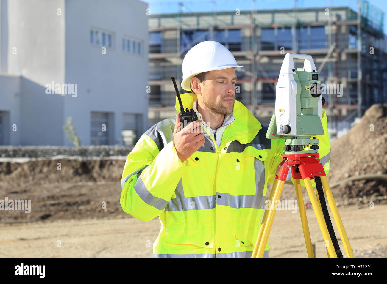 Ein Vermesser mit Vermessung Instrument und Radio vor einem neuen buillding Stockfoto