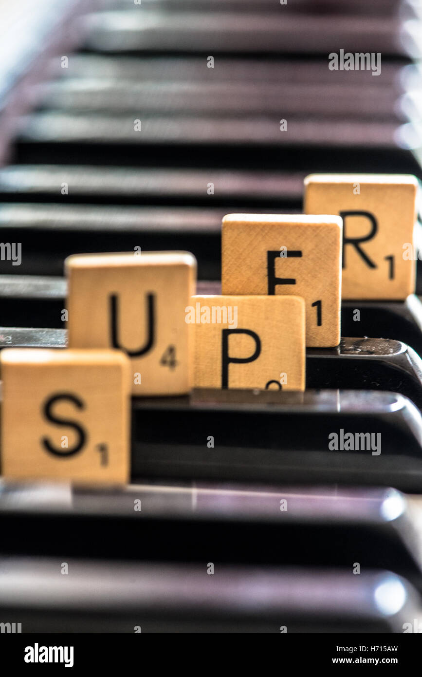 das Wort super geschrieben mit Holzbuchstaben am Klavier Stockfoto