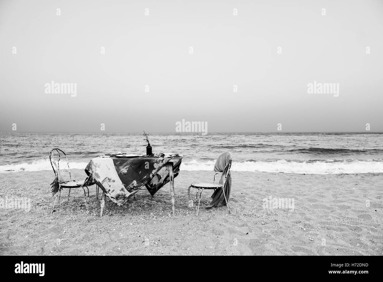 Tisch Stühle Mahlzeit Meeresufer Ferienkonzept Himmel schwarz und weiß Stockfoto