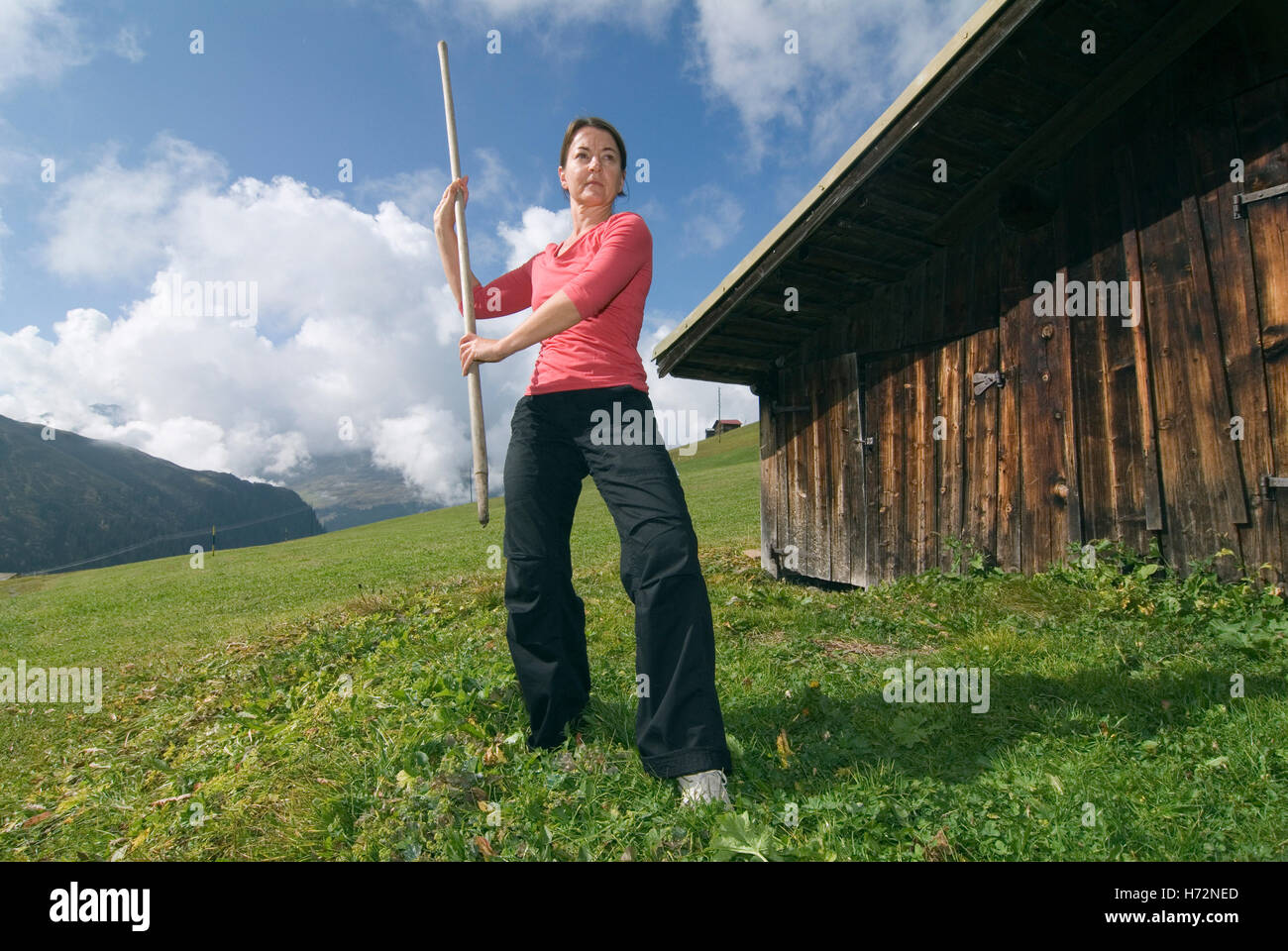 Frau, Anfang 40, Tai Chi zu tun, vor einer Holzhütte in den Schweizer Alpen, Schweiz, Europa Stockfoto