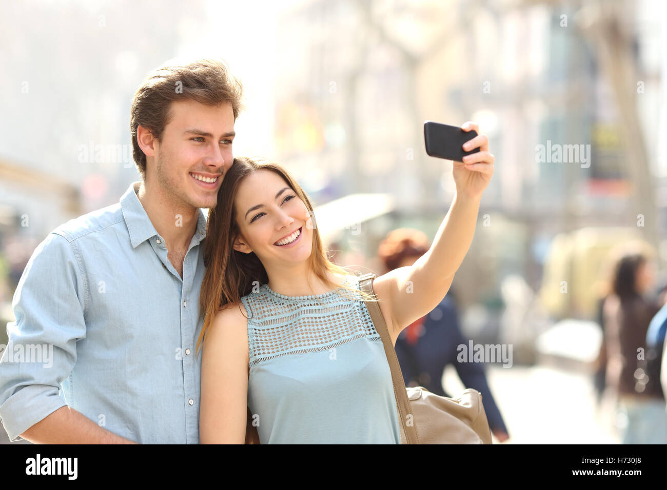 Paar Touristen fotografieren ein Selbstporträt in einer Stadtstraße Stockfoto