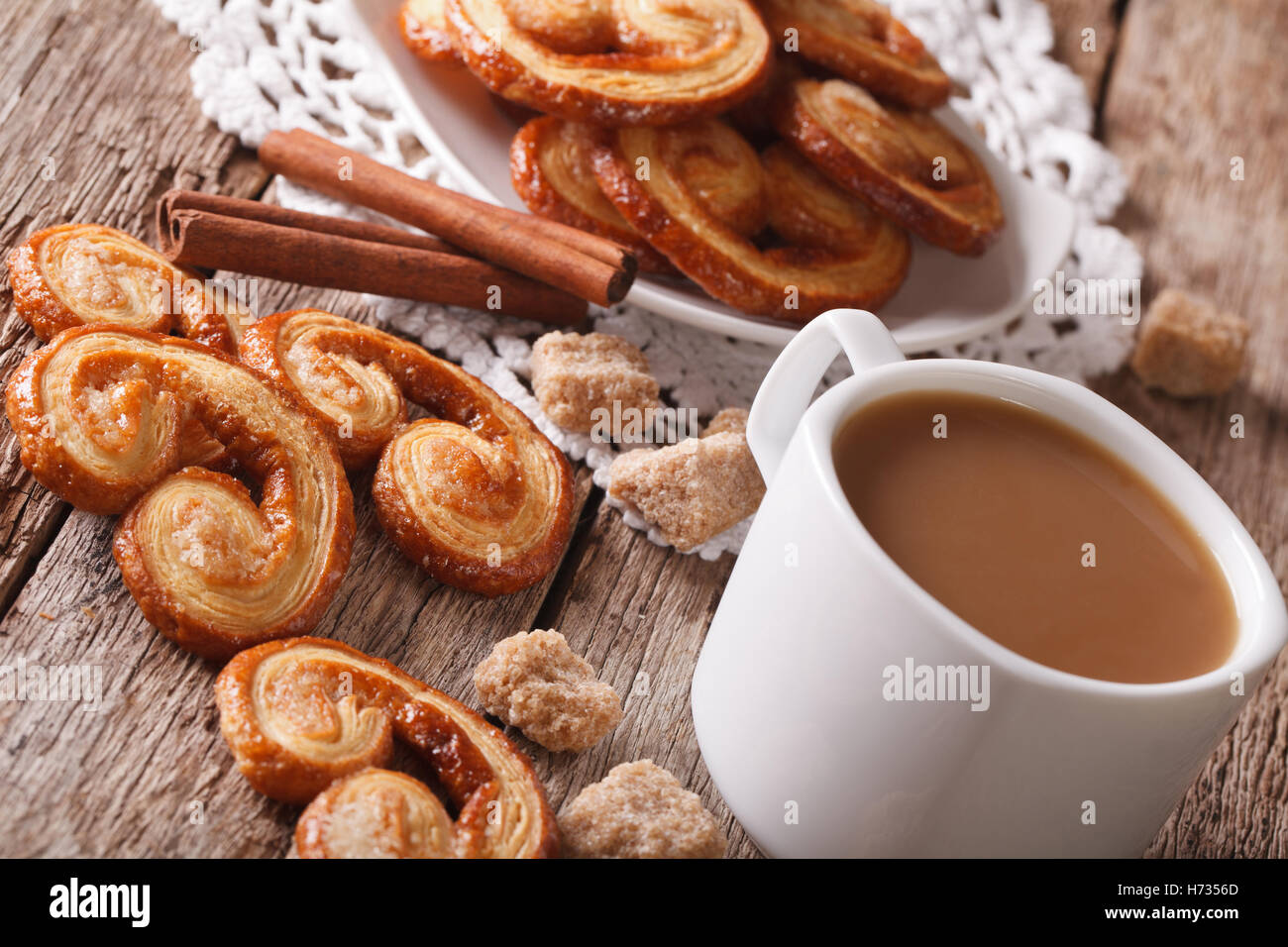 Kekse aus Blätterteig Palmiers und Kaffee mit Milch Nahaufnahme auf einem Tisch, horizontale Stockfoto