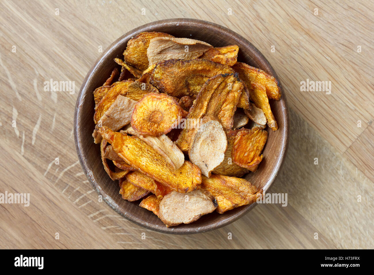 Gebratene Karotten und Pastinaken-chips in rustikalem Holz Schüssel. Von oben. Stockfoto