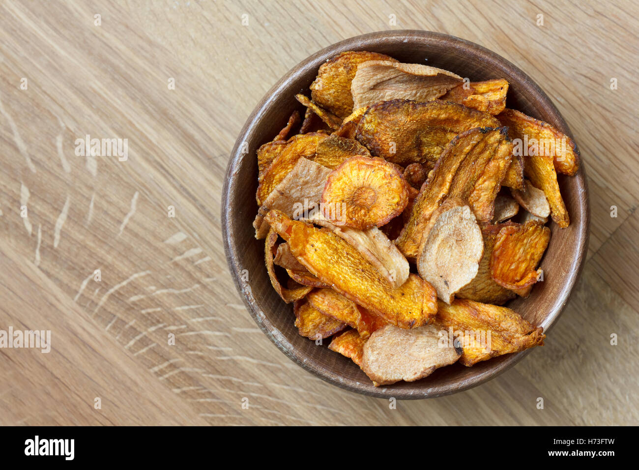 Gebratene Karotten und Pastinaken-chips in rustikalem Holz Schüssel. Von oben. Stockfoto