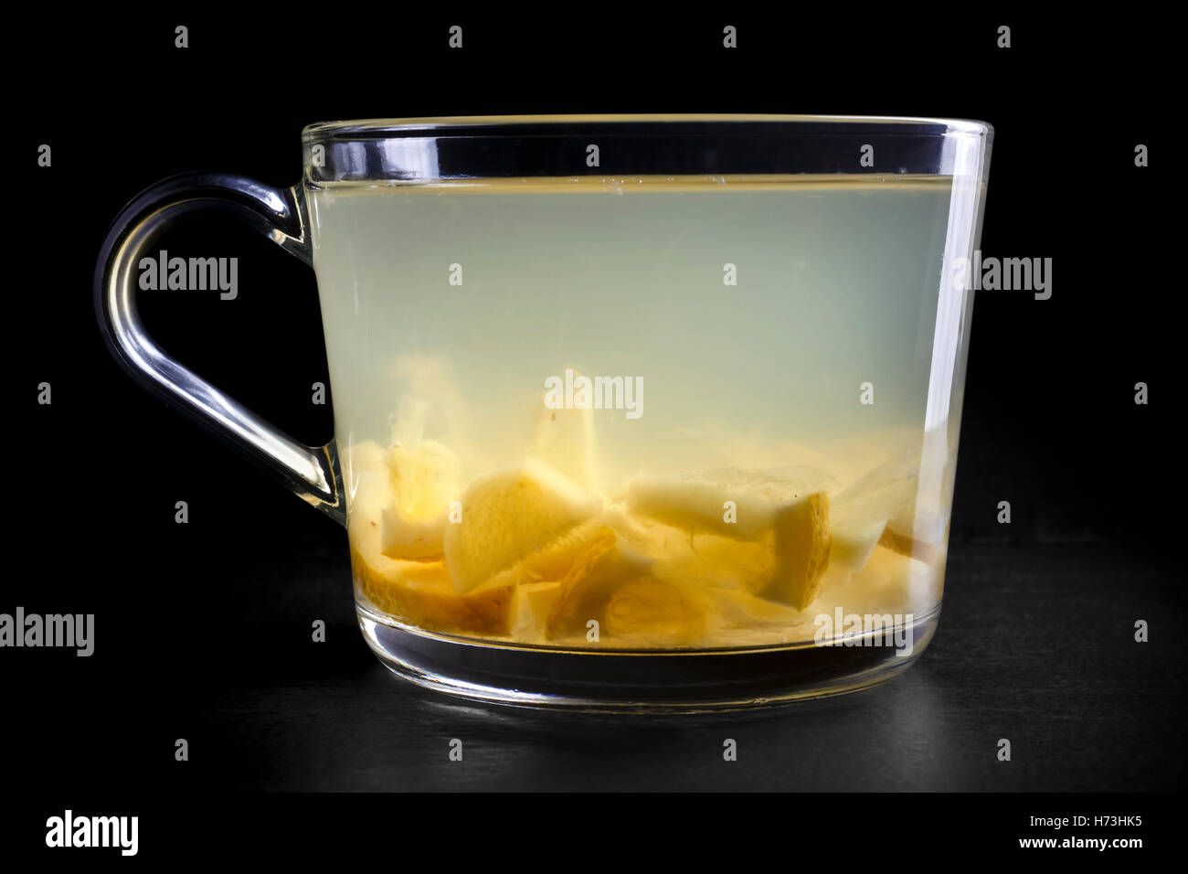 Glas Tasse frischer Zitrone und Ingwer Früchtetee isoliert auf schwarz. Fruchtstücke sichtbar. Stockfoto
