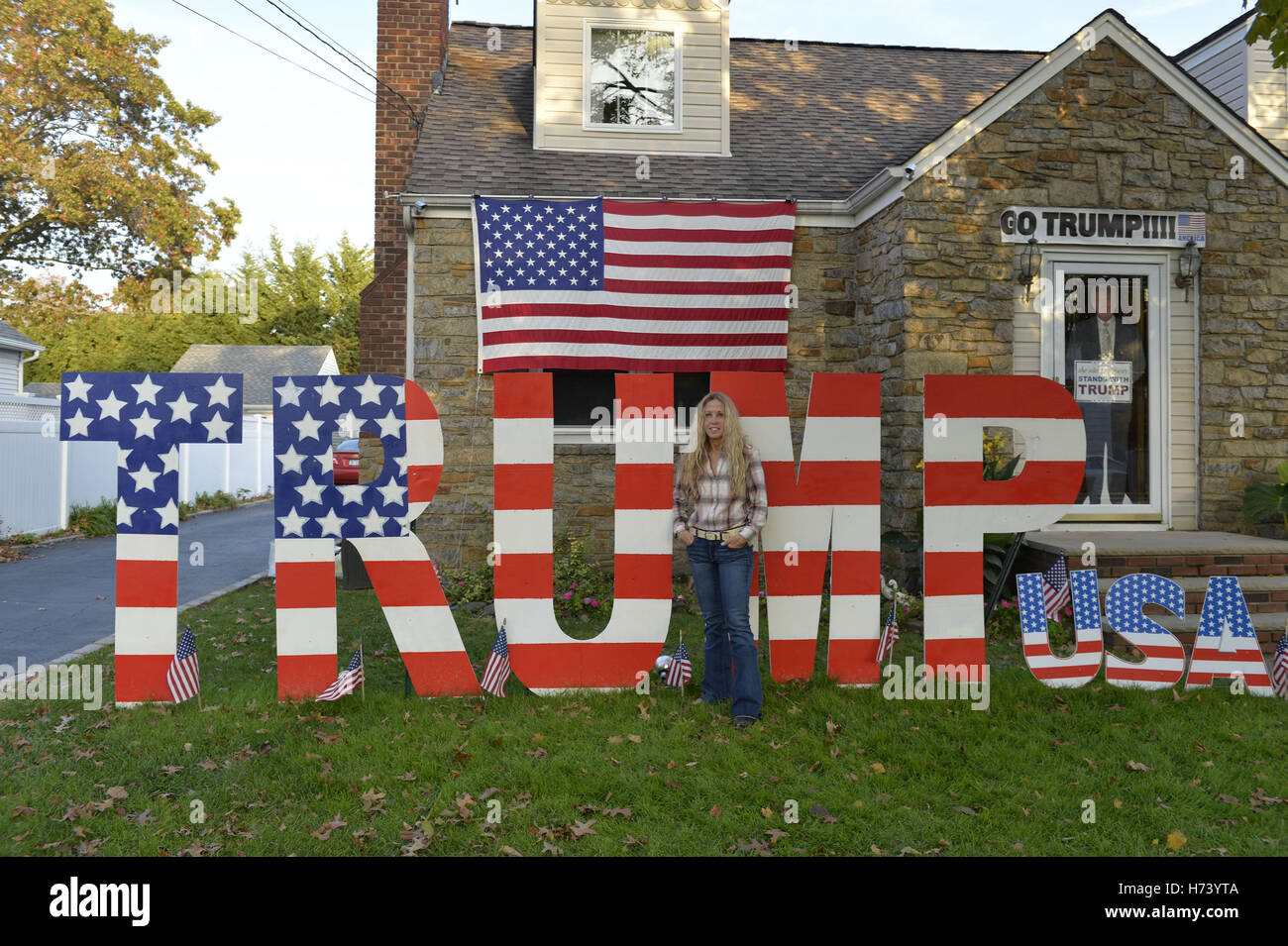 Bellmore, New York, USA. 2. November 2016. EILEEN FUSCALDO, Donald Trump Unterstützer steht vor TRUMP display, einer von vielen in ihrem Vorgarten für den republikanischen Präsidentschaftskandidaten, D. J. Trump, und gegen demokratische eins, H. R. Clinton. Auf ihrer Haustür hält ein lebensgroße Karton Trump '' The Silent Mehrheit steht mit Trump'' Zeichen. Bildnachweis: Ann Parry/ZUMA Draht/Alamy Live-Nachrichten Stockfoto