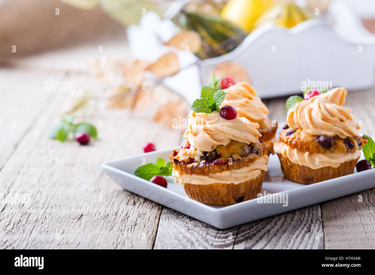 Hausgemachte Herbst Cranberry Kürbis Muffins mit Frischkäse-Glasur auf rustikalen Holztisch Stockfoto