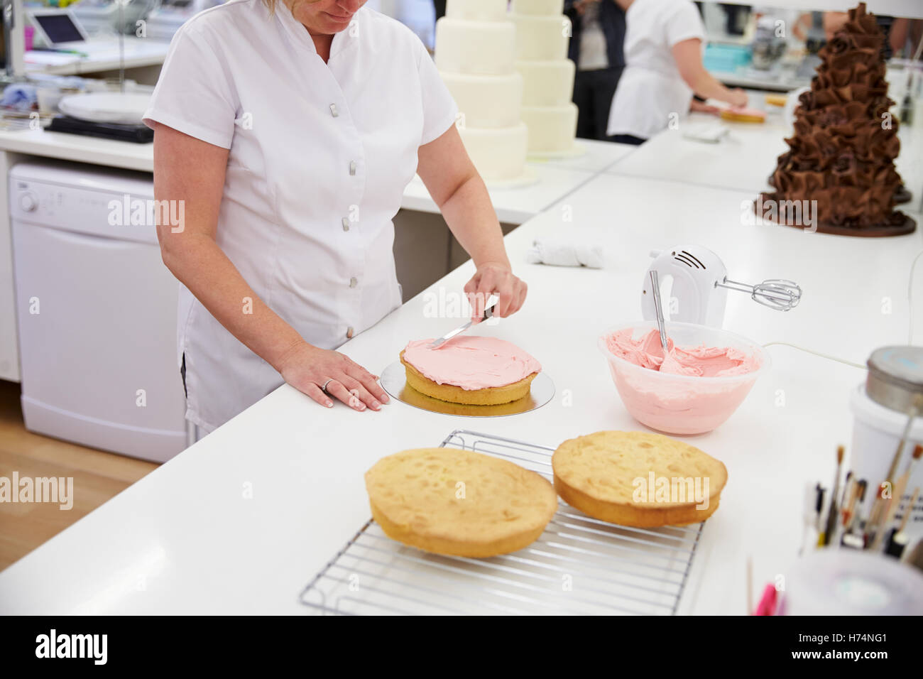 Frau In der Bäckerei Kuchen mit Zuckerguss verzieren Stockfoto