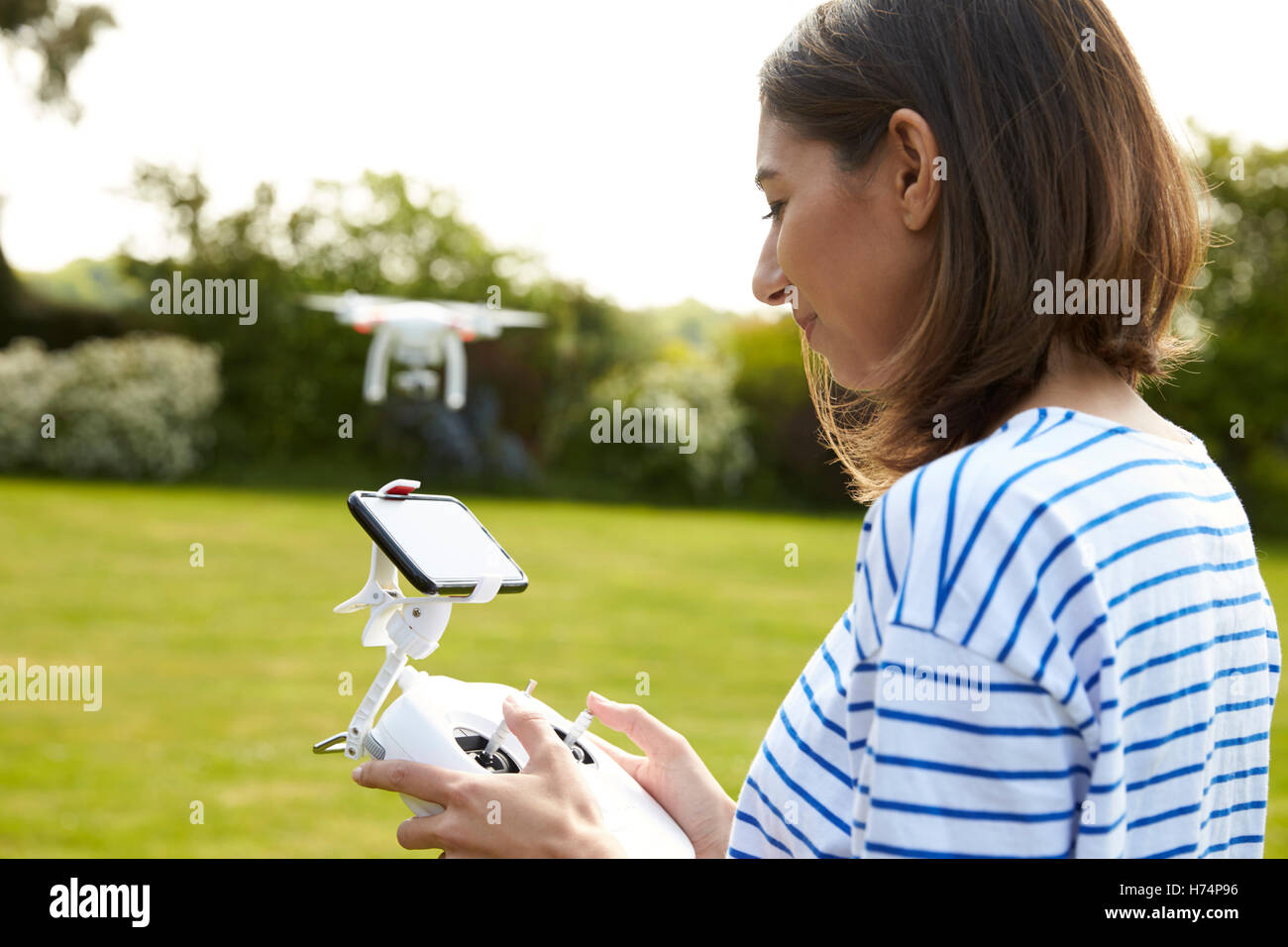 Frau fliegen Drone Quadcopter im Garten Stockfoto