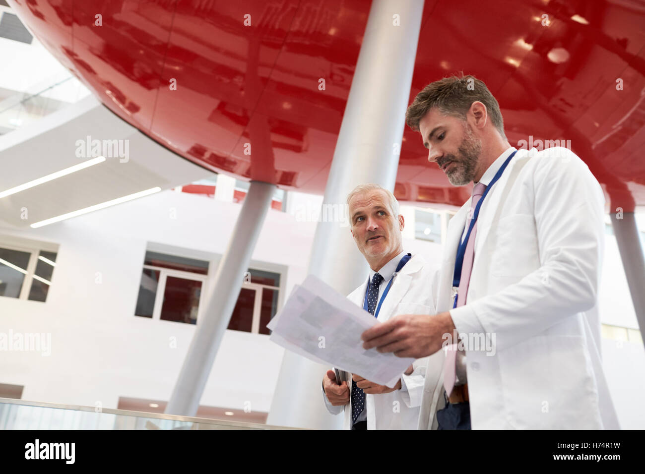 Zwei Ärzte sprechen, wie sie durch moderne Krankenhaus gehen Stockfoto