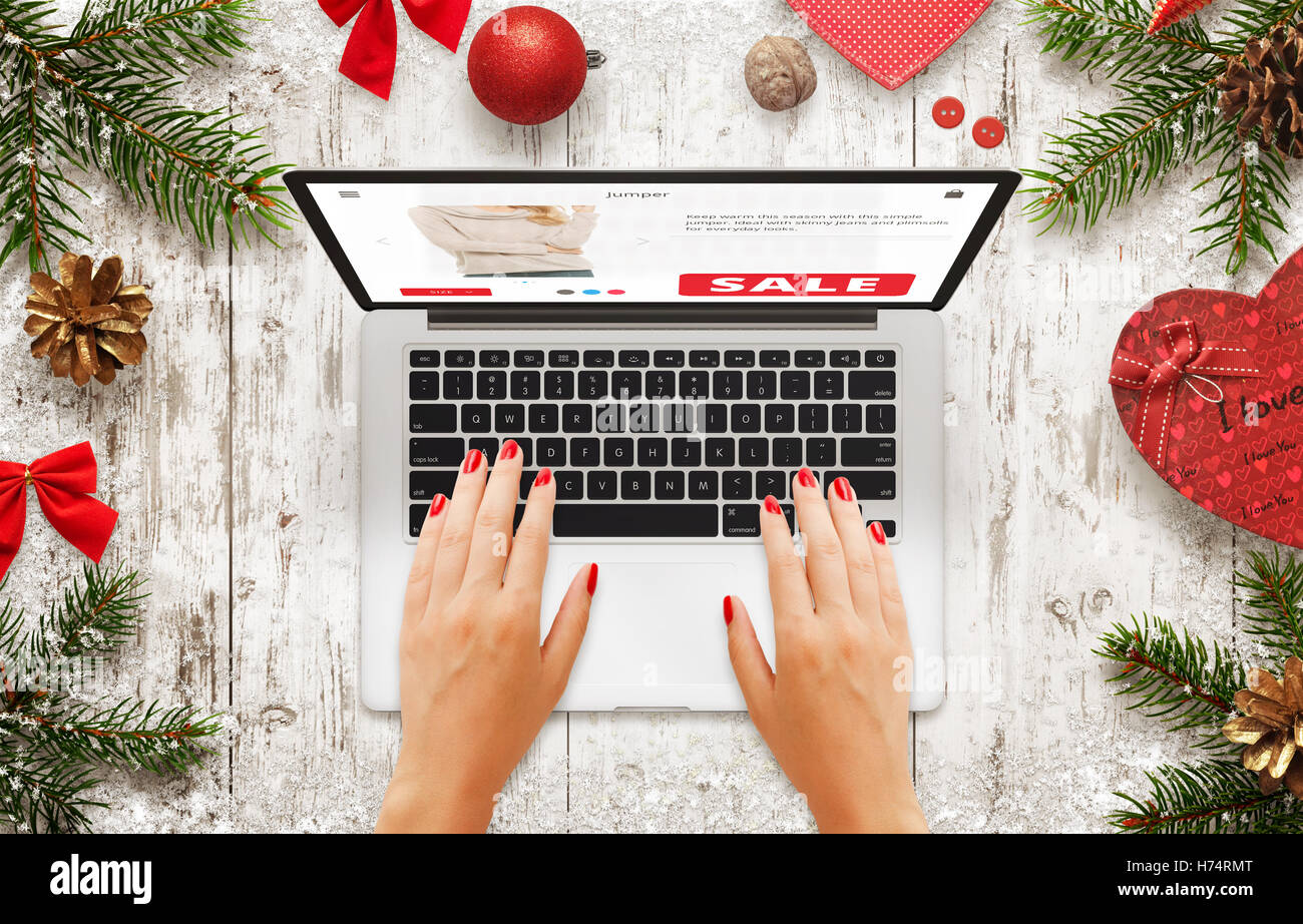 Weihnachtsverkauf auf Laptop. Frau auf Markt Website einkaufen. Draufsicht der Holztisch mit Neujahr Weihnachtsschmuck, Baum ein Stockfoto
