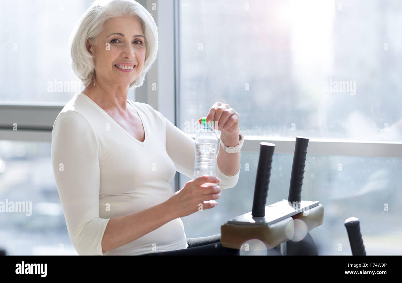 Joyful passen senior Frau Trinkwasser während des Trainings. Stockfoto