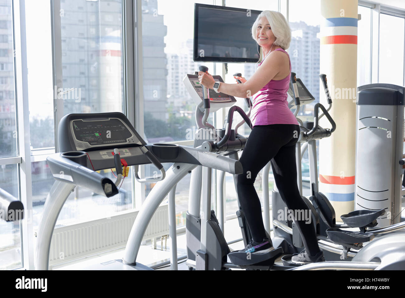 Emotional lächelnd grauen dunkelhaarige Frau Training mit Fitness. Stockfoto