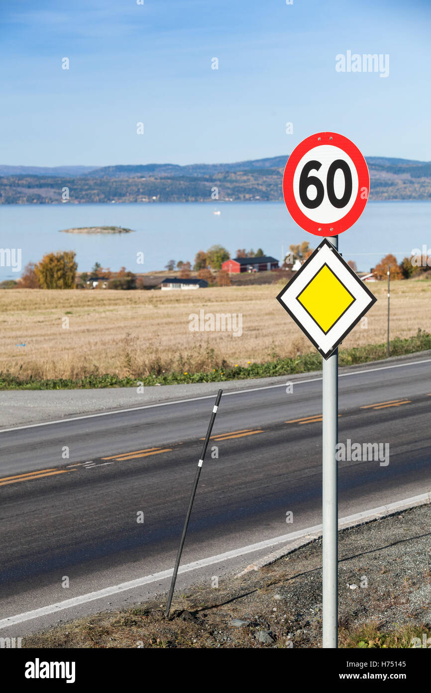 Vertikale Foto von Main Road gelb Roadsign mit Tempolimit Schild montiert auf einer Metallstange in der Nähe von norwegischen Landstraße Stockfoto