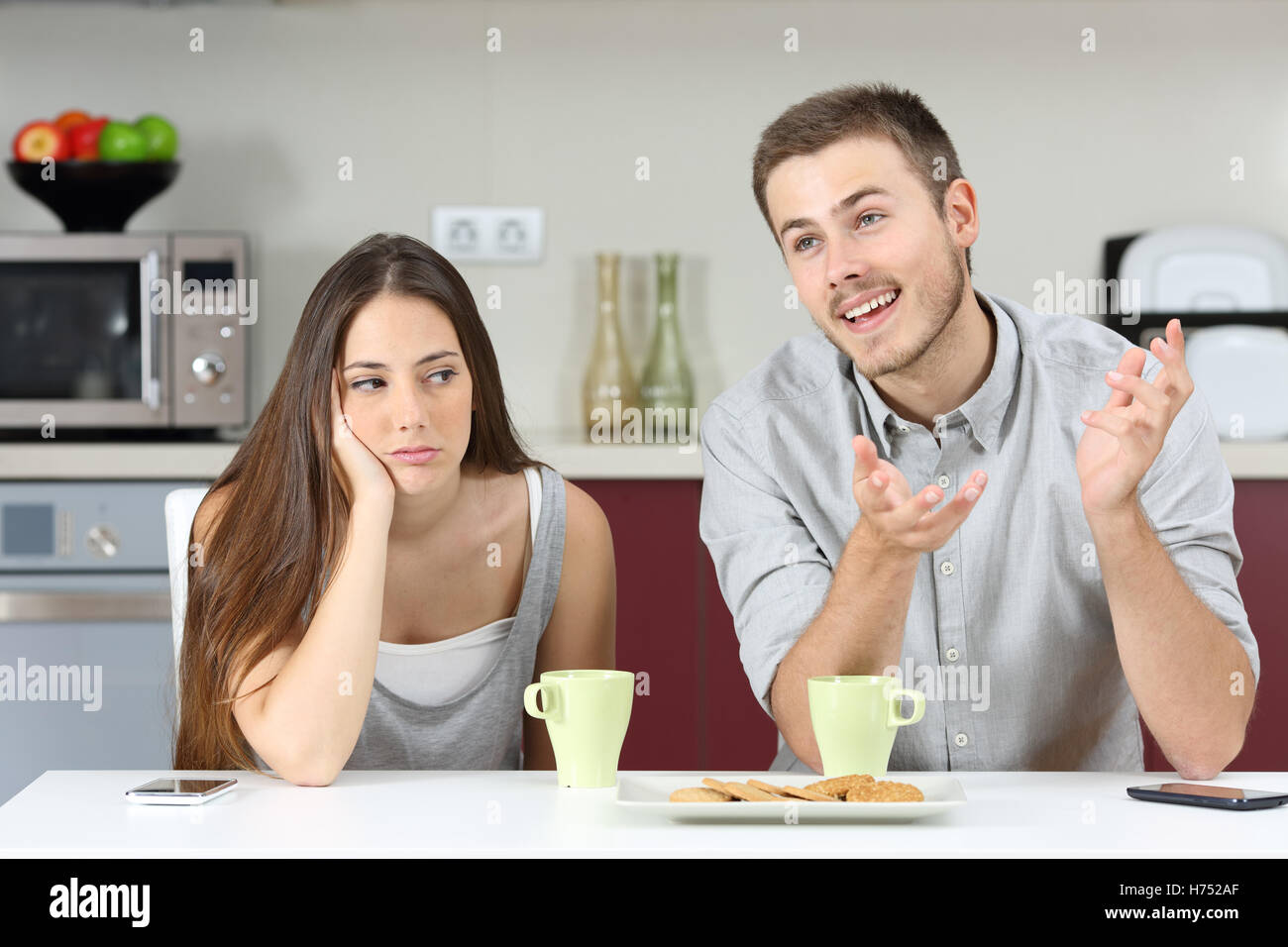 Gelangweilte Frau ihrem Ehemann reden während des Frühstücks in der Küche zu Hause zu hören Stockfoto