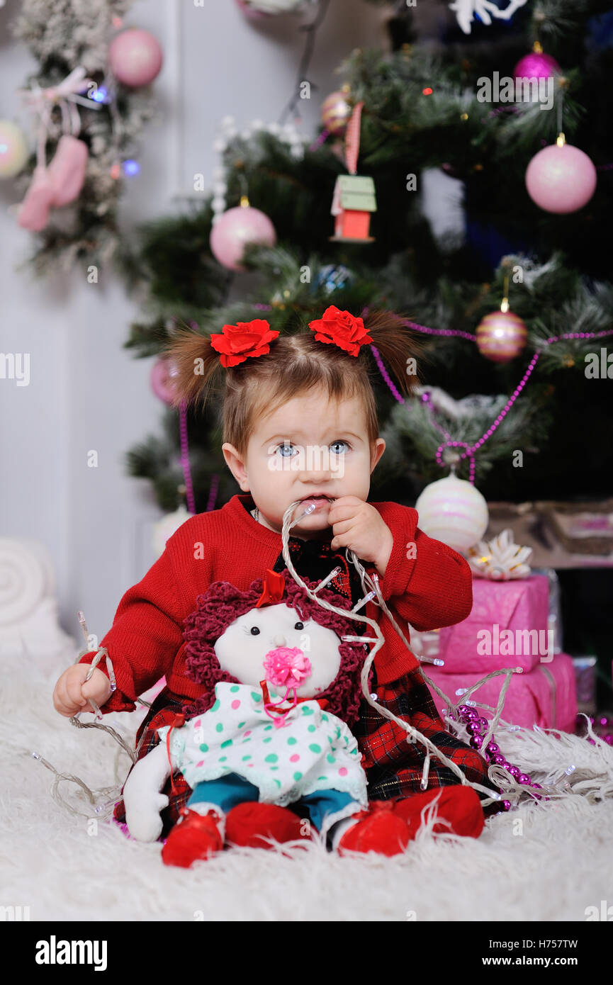 kleines Mädchen in einem roten Kleid auf Grund des Weihnachtsbaumes Stockfoto