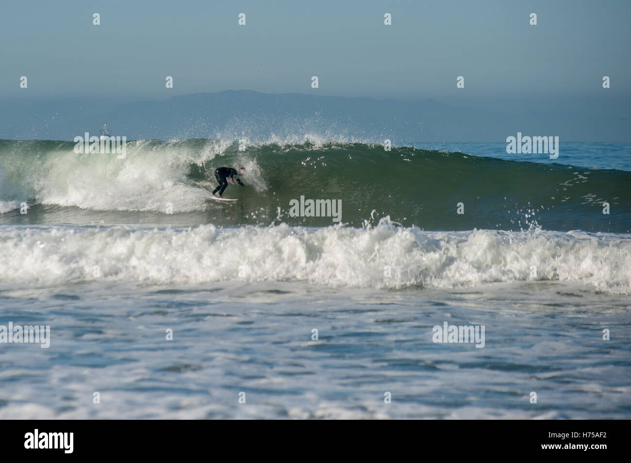 Surfer in schwarzen Neoprenanzug Reiten ein Medium sized Welle links. Stockfoto