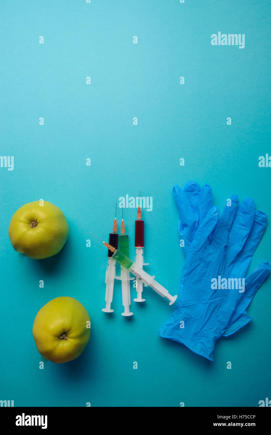 Chemische Zusätze in Lebensmitteln oder genmanipulierte Frucht Konzept. Grüner Apfel mit Spritzen von Chemikalien. Isoliert auf blauen backg Stockfoto
