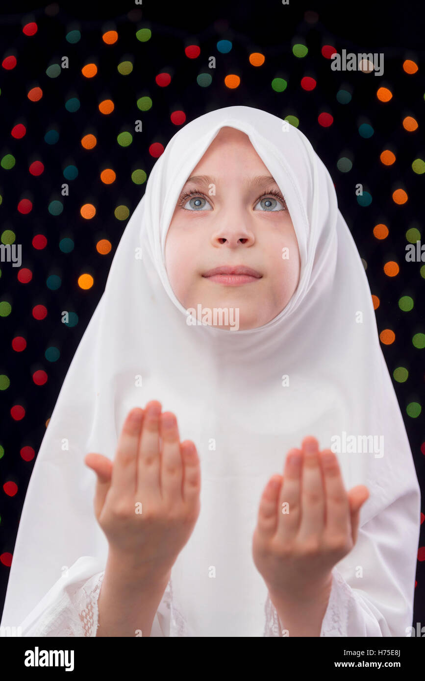 Muslimisches Mädchen beten auf defokussierten Nacht Lichter Hintergrund Stockfoto