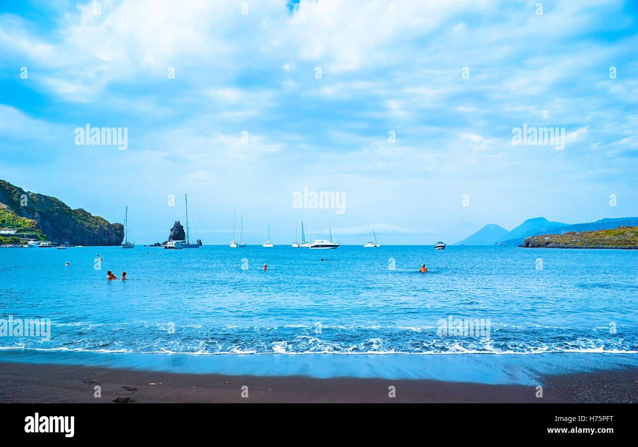 Der schwarze Sandstrand mit Yachten in kleinen Haven und Schwimmen Touristen in Porto di Ponente Stockfoto