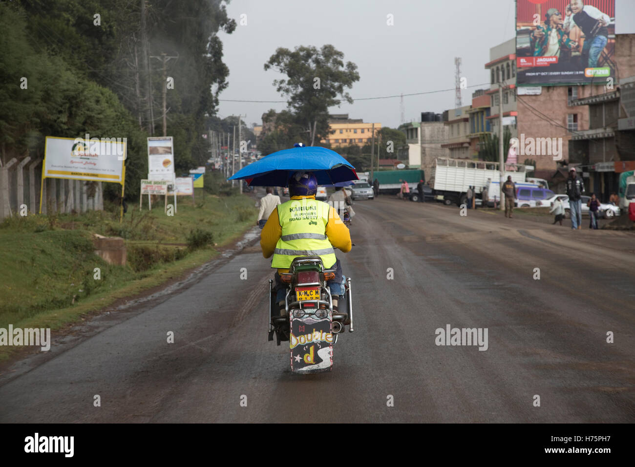 Motorradfahrer und Beifahrer mit Regenschirm auf PikiPiki Motorrad Nanyuki Kenia Stockfoto