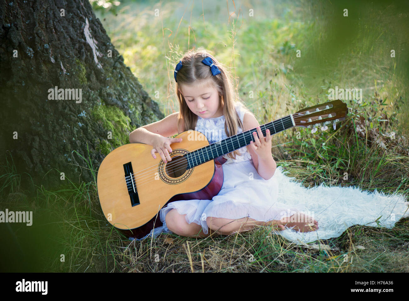 Mädchen sitzen im Wald, die Gitarre zu spielen Stockfoto