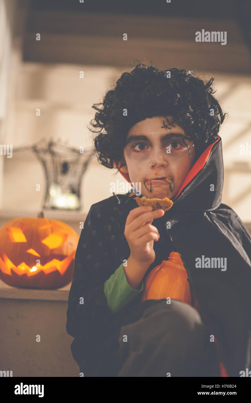 Junge gekleidet in Dracula Halloween-Kostüm mit einem cookie Stockfoto