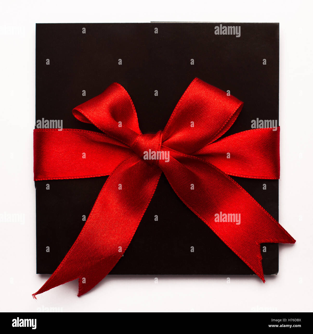 Schwarzes Papierkarte mit rotem Textilband isoliert auf weißem Hintergrund Stockfoto