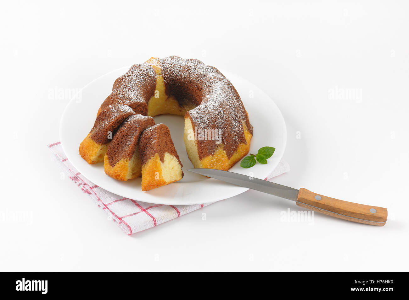 in Scheiben geschnitten Marmor Gugelhupf auf weißen Teller und kariertes Geschirrtuch Stockfoto