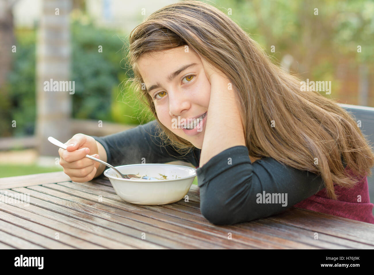 Ein junges Mädchen mit Klammern auf ihre Zähne genießen heiße Hühnersuppe (aka die Jewish Penicillin) in einem kalten Herbsttag Stockfoto
