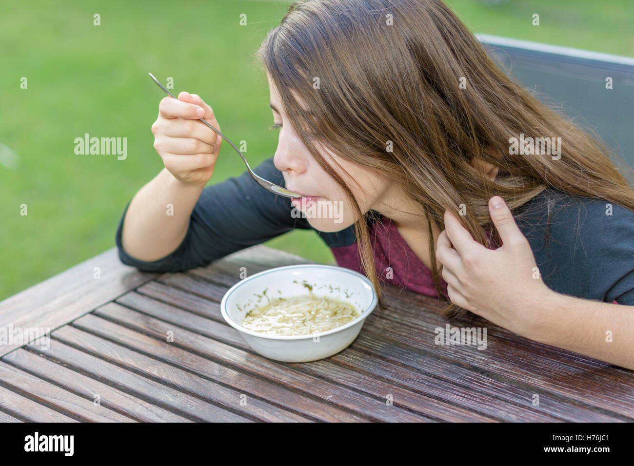 Ein junges Mädchen mit Klammern auf ihre Zähne genießen heiße Hühnersuppe (aka die Jewish Penicillin) in einem kalten Herbsttag Stockfoto