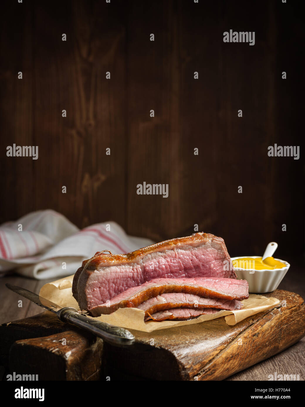 Braten-Oberseite von Rindfleisch in Scheiben geschnitten auf rustikalen Brett mit Topf mit Senf Stockfoto