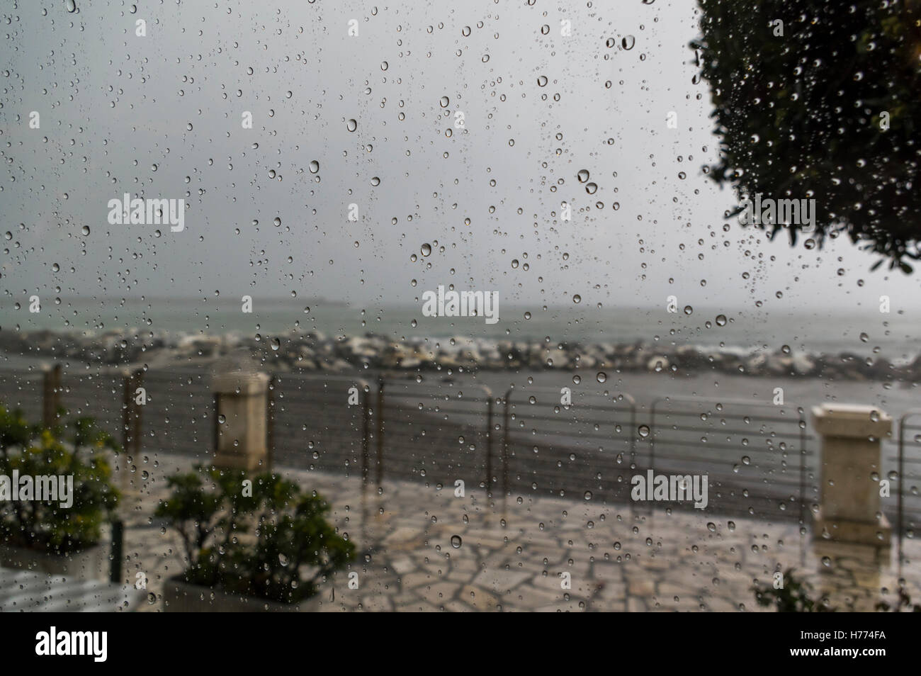 Regentropfen auf einem Fenster während eines Gewitters. Meer und Mittelmeer als Fokus-Hintergrund. Stockfoto