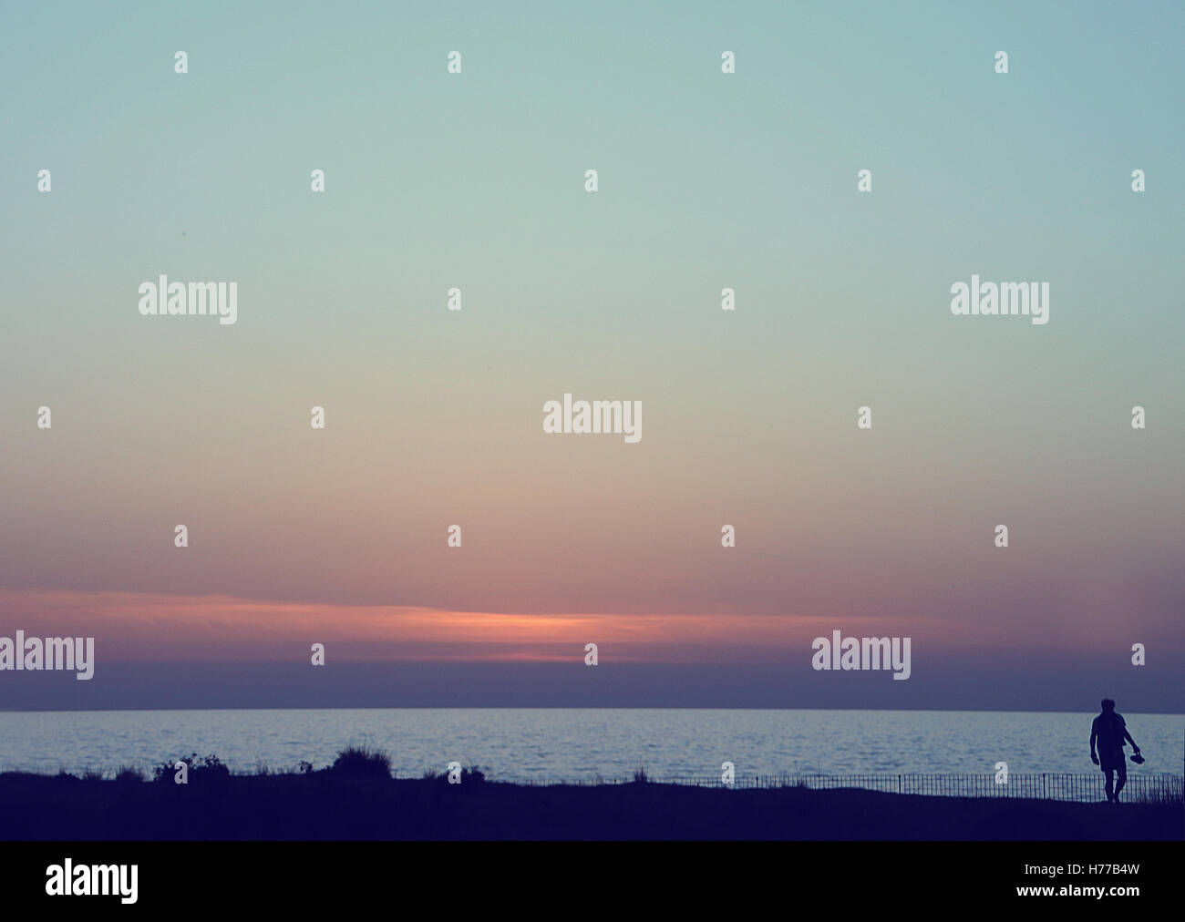 Silhouette eines Mannes zu Fuß am Strand entlang Stockfoto