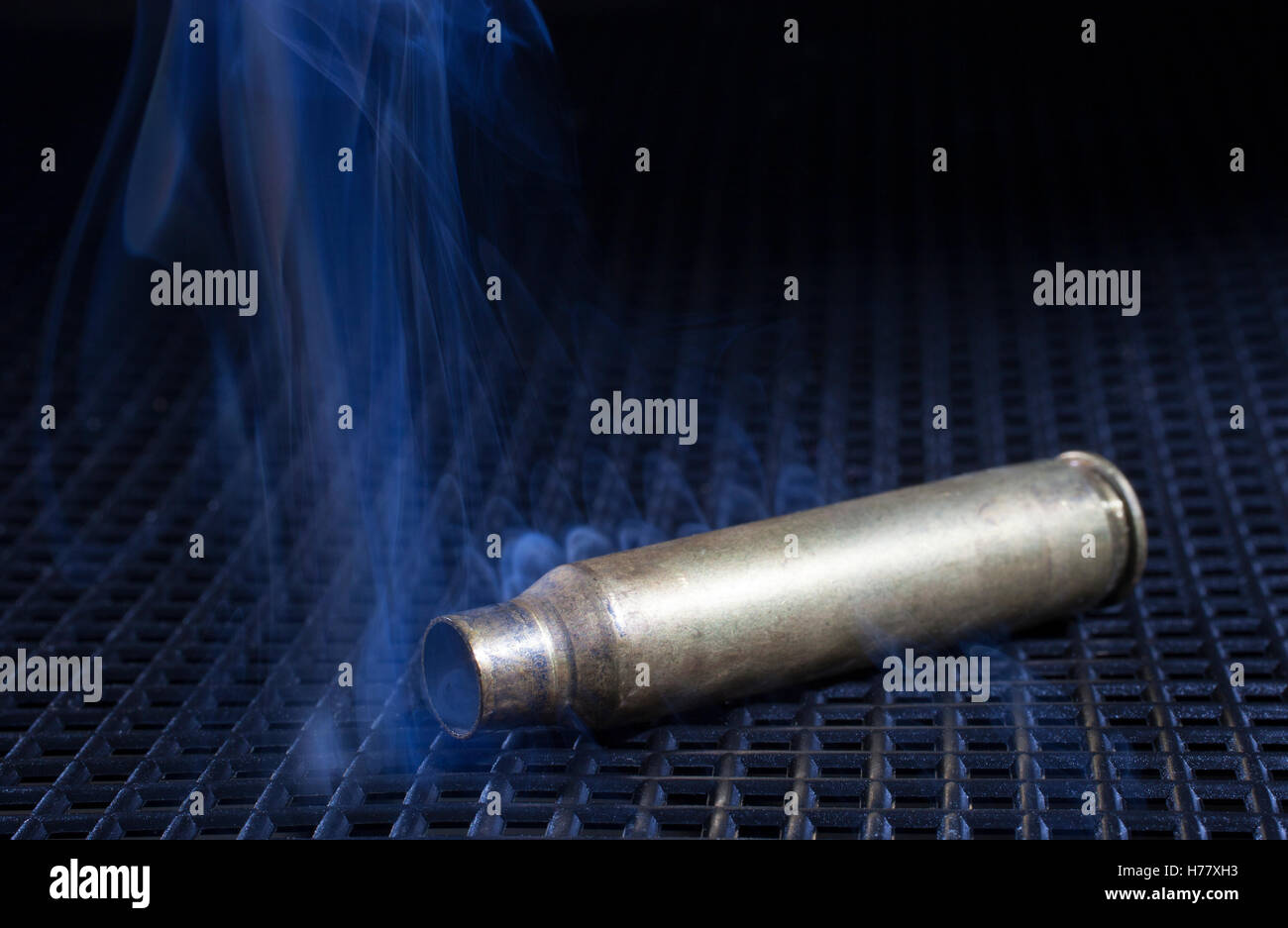 Leerer Koffer aus einem Gewehr mit Rauch auf einen schwarzen Rost Stockfoto