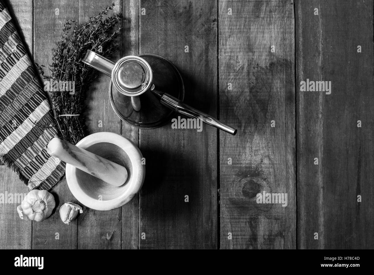 Luftaufnahme des Stilllebens Zutaten zum Würzen von Thymian, Knoblauch Ölkanne und einem Mörser auf einem rustikalen Holztisch in schwarz und Stockfoto