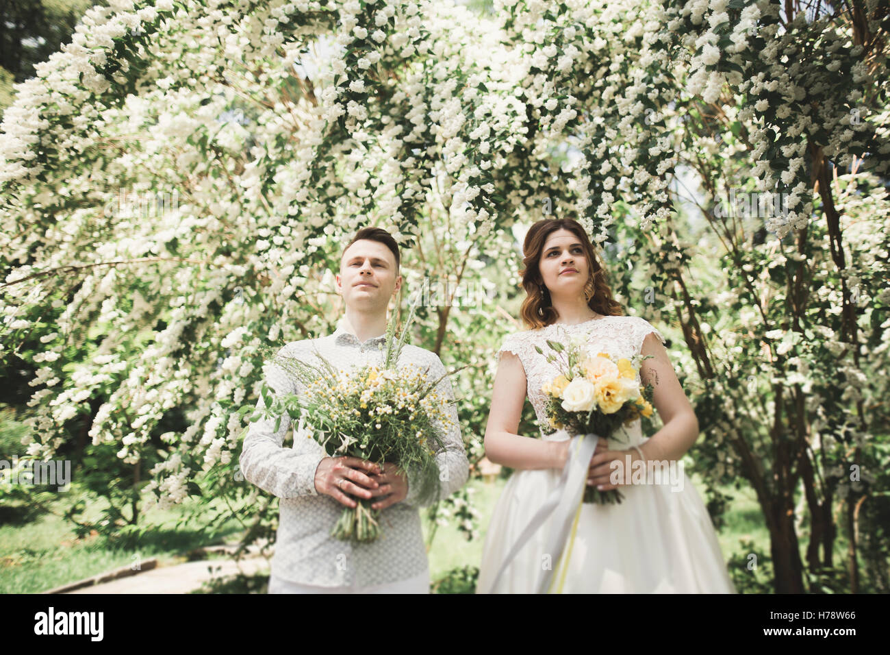 Stilvolle paar glückliche Brautpaar im Park spazieren, am Tag ihrer Hochzeit mit Blumenstrauß Stockfoto