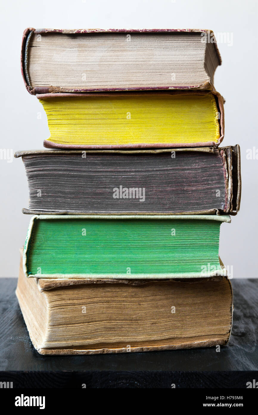 Stapel von alten Vintage Bücher in verschiedenen Farben auf schwarzer Holztisch vor hellen Innenräumen Hintergrund in natürlichem Licht. Stockfoto