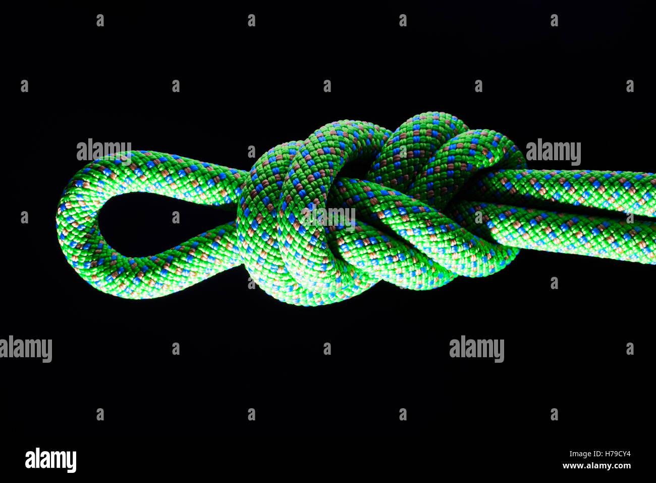 Achter in einer grünen Klettertau mit schwarzem Hintergrund Stockfoto