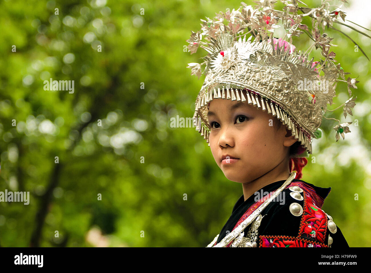 Ein Gilr in Tracht Miao entlang der Straßen von Taijiang, in Guizhou, China Stockfoto