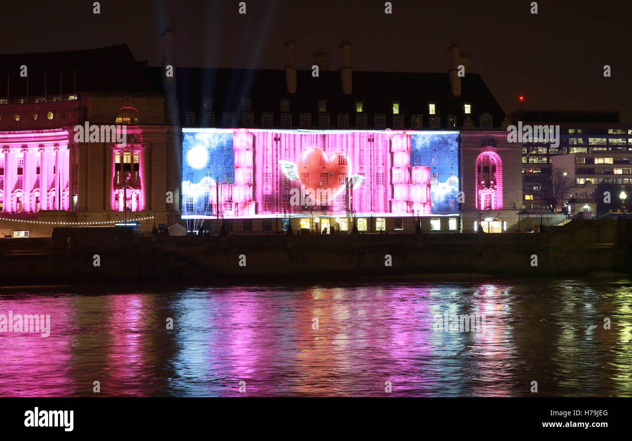NUR zur redaktionellen Nutzung A Projektion auf London County Hall zeigt Online-Händler Very.co.uk Weihnachten Werbung, wie die hand 100 Geschenk-Geber aus rosa Geschenke an Passanten auf Westminster Bridge in London. Stockfoto