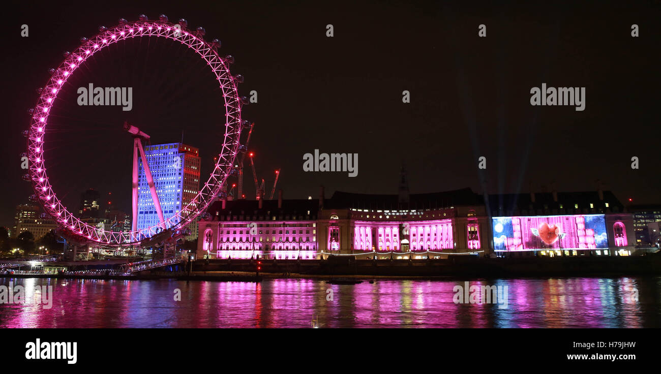 Eine Projektion auf der London County Hall, in der der Online-Händler Very.co.uk's eine Weihnachtsanzeige zeigt, in der 100 Geschenkgeber rosa Geschenke an Passanten auf der Westminster Bridge in London aushändigen. Stockfoto