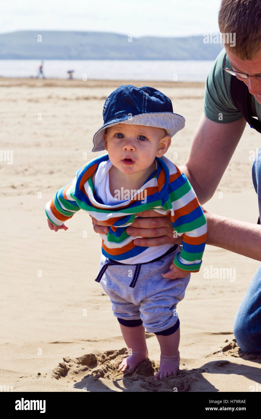Vater seinen Sohn am Strand aufrecht halten Stockfoto