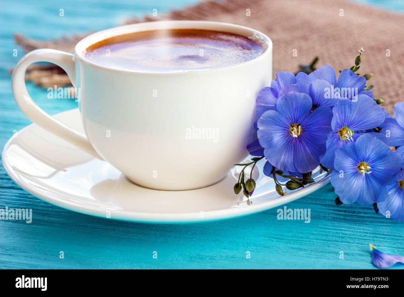 Kaffeebecher mit weißen Blüten und Notizen guten Morgen Frühstück am blauen rustikalen Tisch von oben, Stockfoto