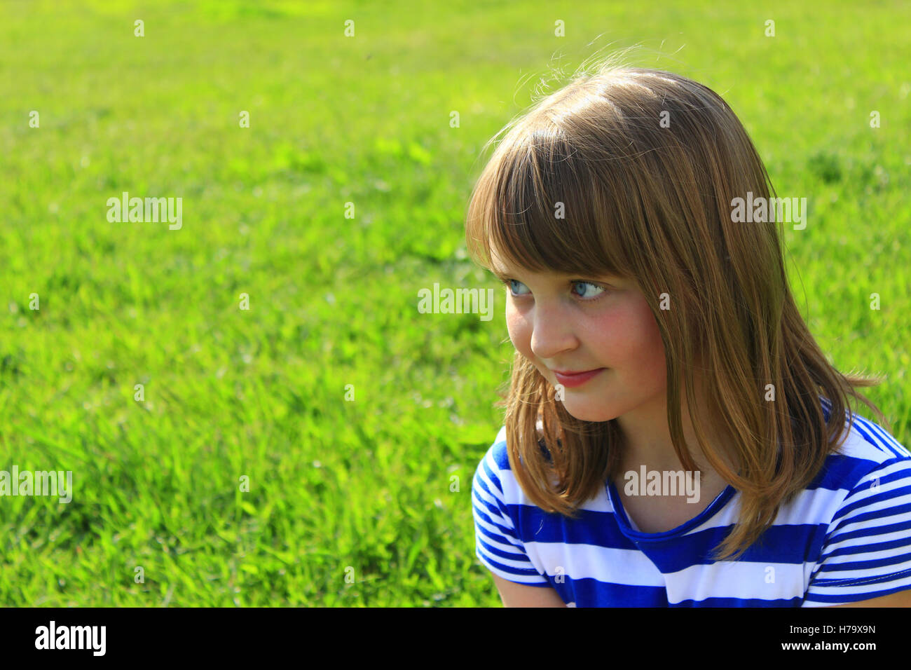 modische Mädchen grinst auf dem grünen Rasen-Hintergrund Stockfoto