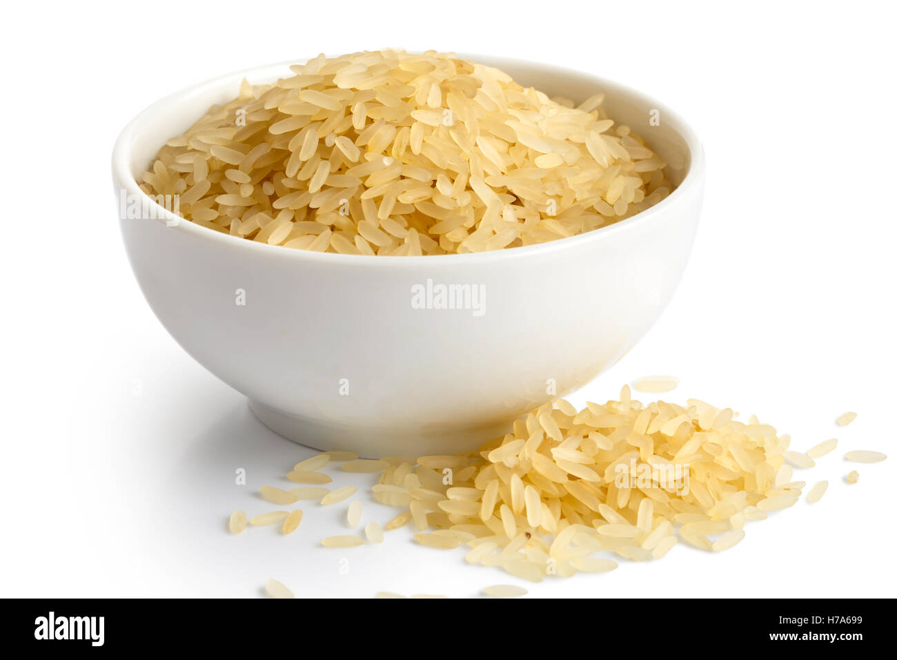 Schüssel mit Langkorn parboiled Reis isoliert auf weiss. Verschüttete Reis. Stockfoto